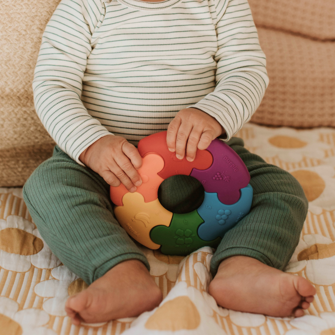 Baby holding rainbow silicone colour wheel