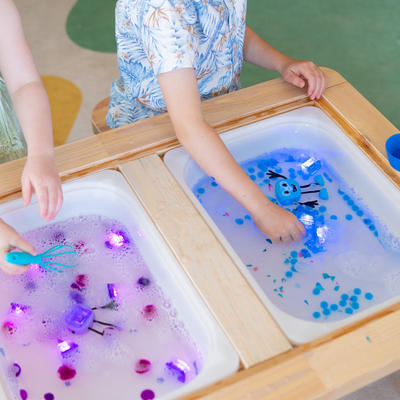 Kids playing with light up cubes in a sensory tray