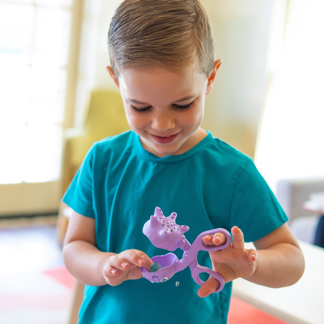 Boy holding purple scoop for sensory play
