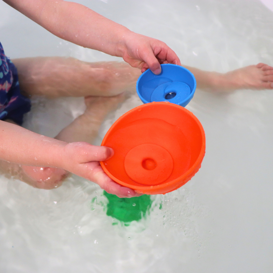 Girl playing with stacking cups in the bath