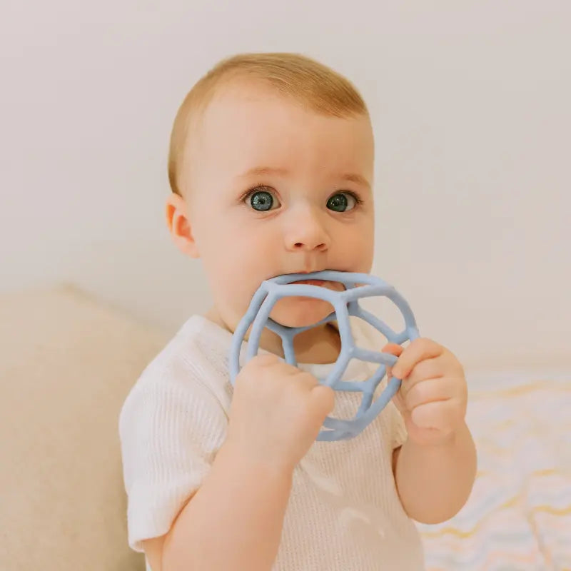 Boy chewing blue silicone teething ball 