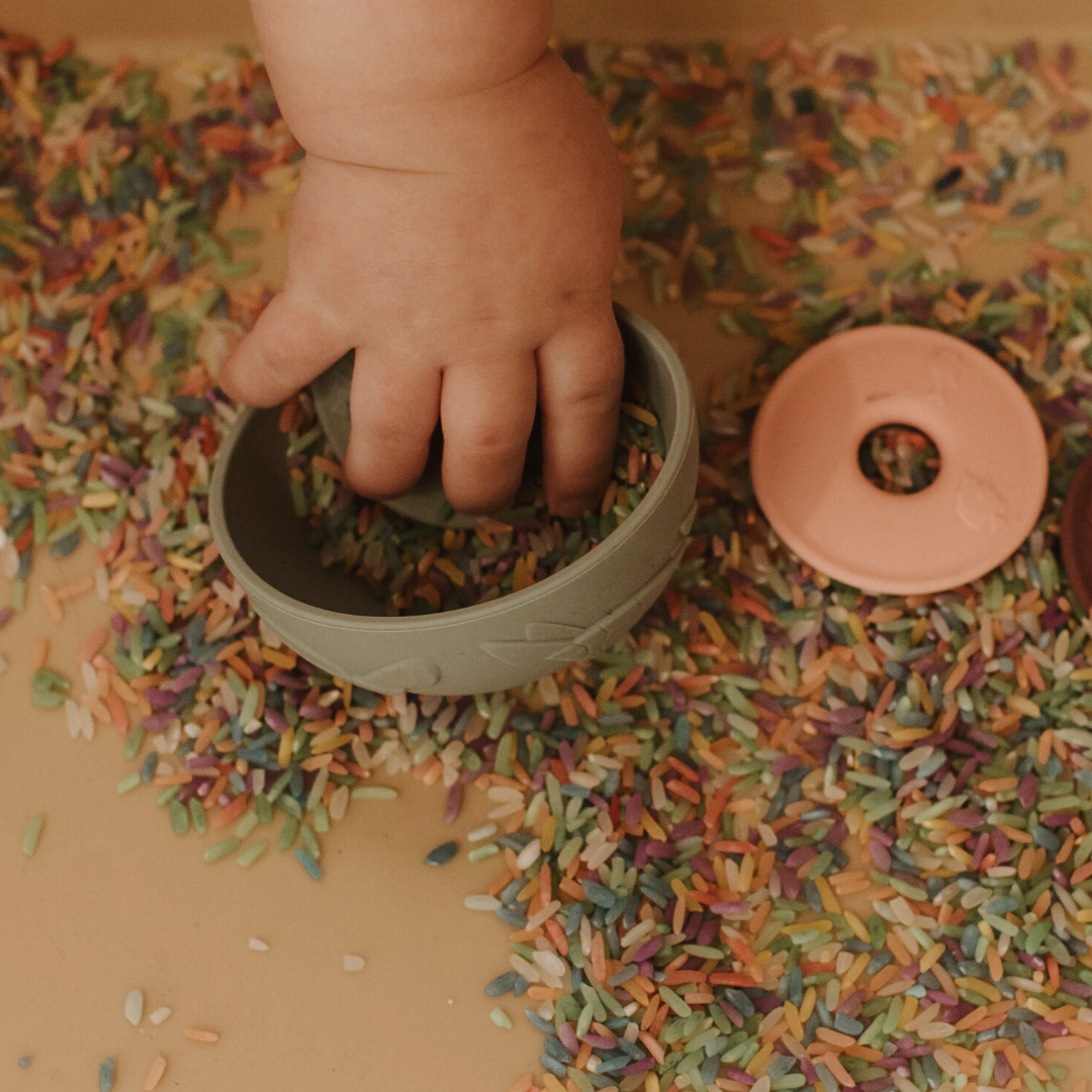 Baby hand playing with sensory rice