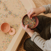Hands spooning colourful rainbow rice in a bowl