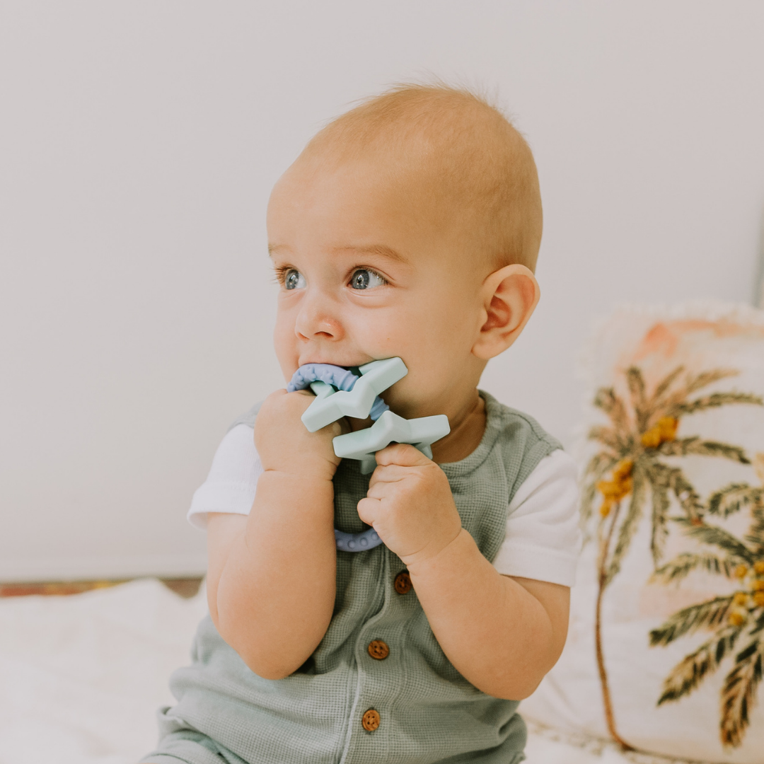 Baby boy chewing on blue star teether