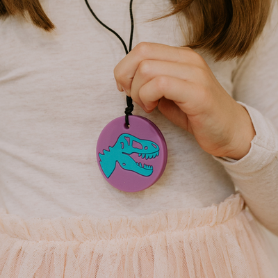 Close up of girl holding dino pendant
