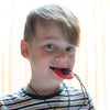 Boy chewing on dino pendant
