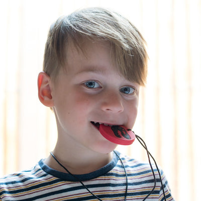Boy chewing on dino pendant