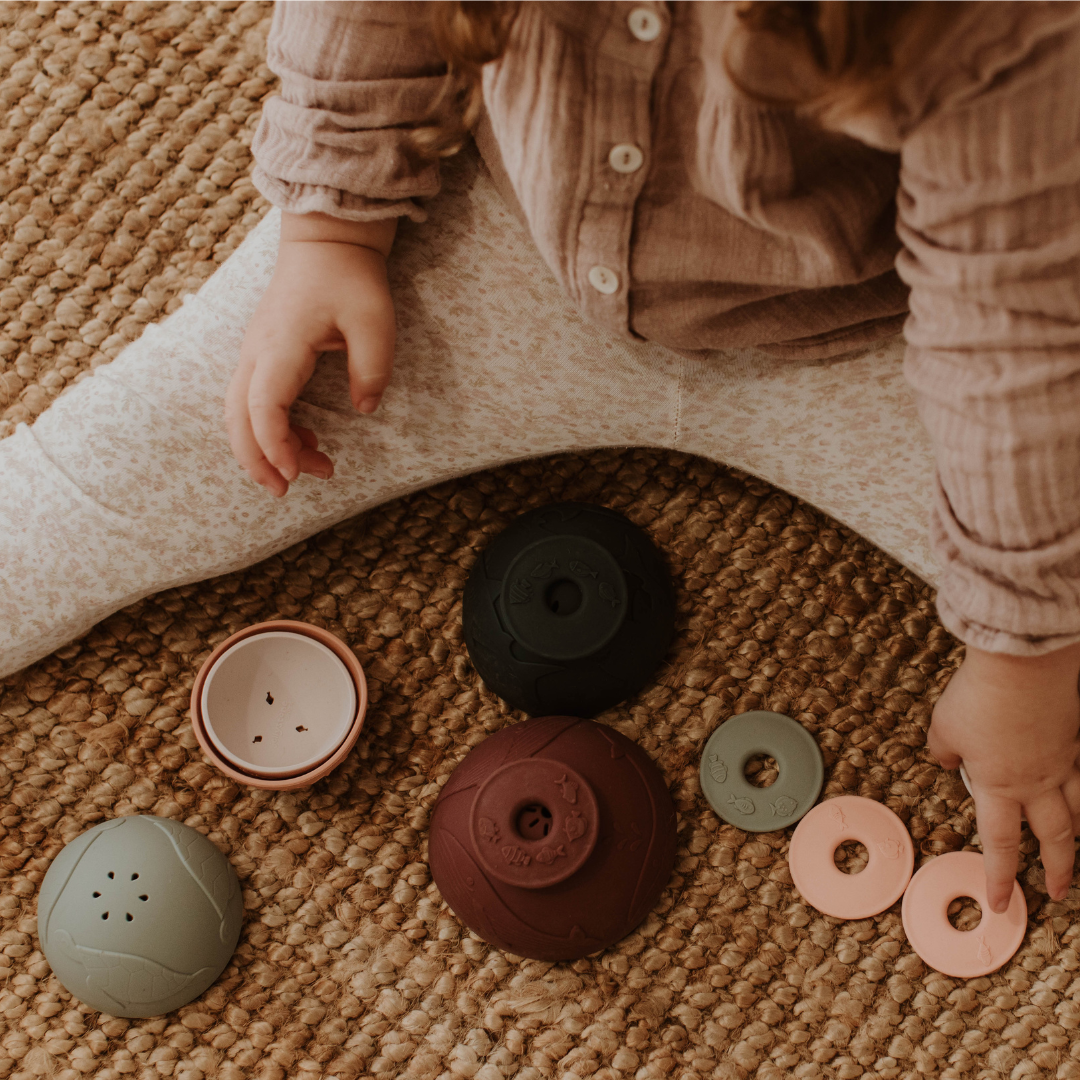 Baby girl playing with earth stacking cups