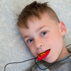 Boy chewing on his strike energy pendant